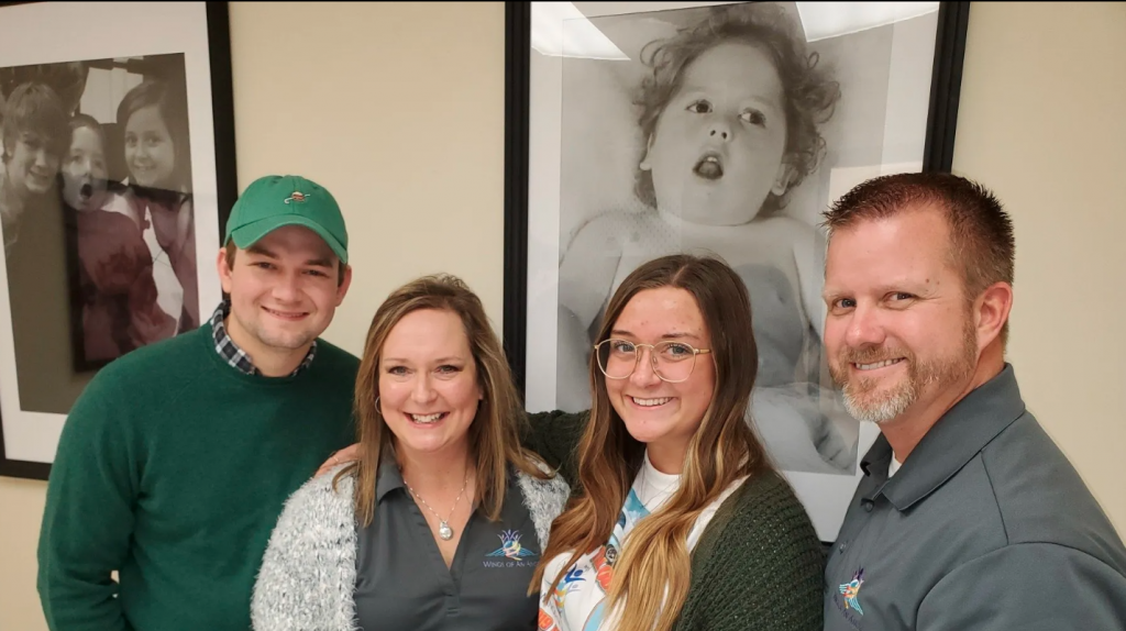 The Ballinger Family poses at their new ADS facility with pictures of Blake in the background.