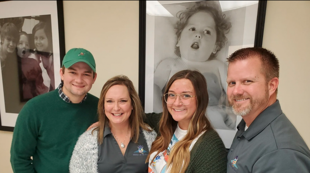 The Ballinger Family poses at their new ADS facility with pictures of Blake in the background. 